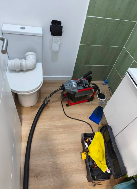 Canalizador com luvas pretas a apertar tubagem de lava-loiça